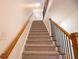 Carpeted staircase featuring wooden railing with black metal spindles leads to the upper level at 319 Barbados Ln, Suwanee, GA 30024