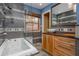 Well-lit bathroom with a built-in tub, walk-in shower, wood cabinets and unique tiling throughout at 625 Kennesaw Ave, Atlanta, GA 30308