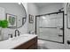A modern bathroom features a vanity, round mirror, and a glass-enclosed shower with a black frame at 6250 Vista Crossing Way, Cumming, GA 30028
