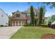 Traditional brick home showcasing manicured front lawn, professional landscaping, and a spacious three-car garage at 6250 Vista Crossing Way, Cumming, GA 30028