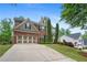 Traditional brick home showcasing manicured front lawn, professional landscaping, and a spacious three-car garage at 6250 Vista Crossing Way, Cumming, GA 30028