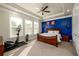Large bedroom suite with a royal blue accent wall, tray ceiling, and windows at 2080 Abbey Rd, Roswell, GA 30076