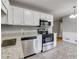 Charming kitchen offers white cabinetry, stainless appliances, and grey tile flooring at 1094 Plantation Ct, Villa Rica, GA 30180