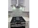 Modern kitchen with a stainless steel range, hood, white cabinets, and backsplash with horizontally laid tiles at 503 Glendale Rd, Scottdale, GA 30079