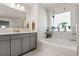 Bright bathroom with modern vanity, soaking tub, and natural light streaming through the window with green plants at 1180 Trident Maple, Lawrenceville, GA 30045