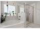 Clean bathroom featuring soaking tub with green plants and a sleek glass-enclosed shower with marble tiles at 1180 Trident Maple, Lawrenceville, GA 30045
