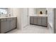 Bright bathroom with double sink vanity, sleek gray cabinets, white counter tops, and marble tiled floor at 1180 Trident Maple, Lawrenceville, GA 30045