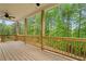 Spacious covered deck featuring wood flooring, ceiling fan and an expansive view of the surrounding trees at 1180 Trident Maple, Lawrenceville, GA 30045