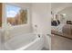 Modern bathroom featuring a soaking tub, a window with a nature view, and an open door to the bedroom at 115 Maplewood Ln, Conyers, GA 30094