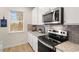 Modern kitchen with gray backsplash, stainless steel microwave, and an electric cooktop at 115 Maplewood Ln, Conyers, GA 30094