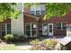 Brick exterior view showcasing large windows, a patio, and blooming flower bushes at 601 Hexham Ct, Suwanee, GA 30024