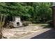 Outdoor stone fireplace feature with a stone patio surrounded by lush landscaping at 601 Hexham Ct, Suwanee, GA 30024