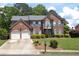 Beautiful brick home featuring a manicured lawn, mature trees, and classic shuttered windows at 601 Hexham Ct, Suwanee, GA 30024