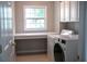 Well-organized laundry room with modern appliances, built-in shelves and a window for natural light at 601 Hexham Ct, Suwanee, GA 30024