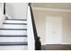 Close-up of a staircase with white spindles, black handrail, and dark wood treads, leading to an upper level at 601 Hexham Ct, Suwanee, GA 30024