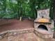 Outdoor stone fireplace with patio and play set, set amongst mature trees in backyard at 1045 River Pt, Suwanee, GA 30024