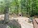 A stone backyard patio featuring an outdoor fireplace and comfortable seating, surrounded by lush greenery and trees at 1045 River Pt, Suwanee, GA 30024