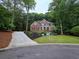 Inviting brick home nestled among trees, with professional landscaping, and a curved driveway at 1045 River Pt, Suwanee, GA 30024