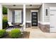 Inviting front porch with seating, modern door, stone accents, and manicured landscaping at 129 Prominence Ct, Canton, GA 30114