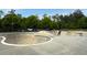Concrete skate park with bowls, ramps, and a person riding a skateboard. Set among green trees at 4824 Dunwoody Station Dr, Atlanta, GA 30338