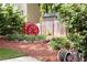 Landscaped backyard with red mulch, lush plants, wooden fence, and decorative red water wheel feature at 427 Picketts Lake Dr, Acworth, GA 30101