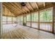 Inviting screened porch with wooden floors, ceiling fan, porch swing, and a beautiful view of the outdoors at 9985 Lake Forest Way, Roswell, GA 30076