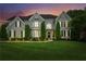 An elegant two-story home at dusk featuring a manicured lawn and traditional architectural details at 110 Keswick Way, Alpharetta, GA 30022