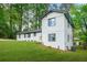 Back of home featuring white painted brick, black trim, well manicured lawn and mature trees at 2813 Hillside Rd, Smyrna, GA 30080
