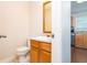 Compact half bathroom with wood vanity and mirror; offers partial view into the kitchen at 5857 Cobalt Dr, Powder Springs, GA 30127