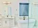 Bright bathroom featuring a modern vanity, a soaking tub, and marble accents throughout the space at 2964 Old Peachtree Rd, Dacula, GA 30019