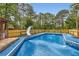 Outdoor swimming pool with a slide surrounded by trees, a fence, and blue poolside flooring at 263 Lynn Dr, Fayetteville, GA 30215
