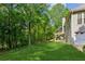 Green backyard with two story home, lush greenery and mature trees at 6990 N Glen Dr, Cumming, GA 30028