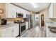 Bright kitchen with white cabinetry, stainless steel appliances, granite countertops, and gray wood-look floors at 6990 N Glen Dr, Cumming, GA 30028