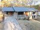 An elevated front exterior featuring a brick home with a long driveway and covered front porch with black railings at 4011 Lake Carlton Rd, Loganville, GA 30052