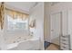 Bright bathroom with a jetted tub, tile surround, and a window at 6932 Dalehollow Dr, Lithonia, GA 30058