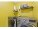 Bright laundry room with yellow walls and stainless steel washer and dryer at 6932 Dalehollow Dr, Lithonia, GA 30058