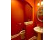 Stylish powder room with an oval mirror, pedestal sink, and vibrant orange walls at 7550 Star Magnolia, Lithonia, GA 30058