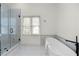 Bright bathroom featuring a glass shower, white freestanding tub, and marble tile flooring at 1130 Lochshyre Way, Lawrenceville, GA 30043
