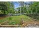 Serene backyard showcasing a well-maintained lawn, mature trees, and a decorative stone border at 1358 Stoneleigh Way, Stone Mountain, GA 30088