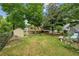 Green backyard featuring mature trees, a shed, a patio, and lush green grass at 1358 Stoneleigh Way, Stone Mountain, GA 30088