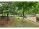 Lush backyard with green grass, mature trees, a storage shed, and a stone-edged garden at 1358 Stoneleigh Way, Stone Mountain, GA 30088