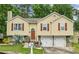 Charming yellow split-level home features brown shutters, attached two-car garage and manicured lawn at 1358 Stoneleigh Way, Stone Mountain, GA 30088