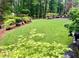 Lush backyard featuring a well-maintained lawn, mature trees, and colorful landscaping at 287 West Wind Dr, Lilburn, GA 30047