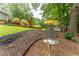 Landscaped backyard featuring mature trees, a well-manicured lawn, and a disc golf basket at 287 West Wind Dr, Lilburn, GA 30047