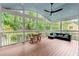 A screened porch with wood floors, a fan, furnishings and views of the wooded yard at 1582 E Bank Dr, Marietta, GA 30068
