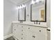 Bright bathroom featuring double sinks, granite counters, framed mirrors, and white cabinetry at 2944 Berry Rd, Loganville, GA 30052