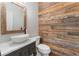Stylish half bathroom with wood wall, white vessel sink, and a decorative mirror at 1605 Little Lisa Ln, Snellville, GA 30078