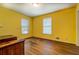 A sunny bedroom with yellow walls and wood floors features two windows with white blinds at 1850 Francis Sw Rd, Conyers, GA 30094