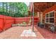 Cozy backyard area with a red fence, landscaping, and a brick-paved area for outdoor enjoyment at 3990 Howell Park Rd, Duluth, GA 30096
