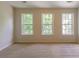 Sunlit bedroom featuring neutral carpet and three large windows providing ample natural light at 3990 Howell Park Rd, Duluth, GA 30096